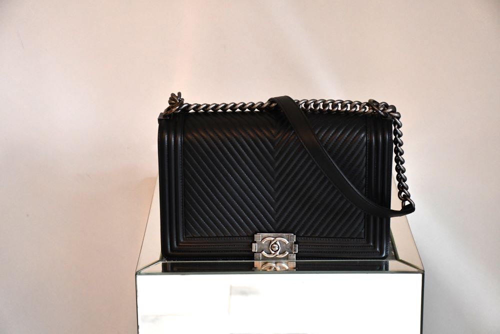 preowned Chanel Chevron Lambs Leather On Chain Boy Bag on table
