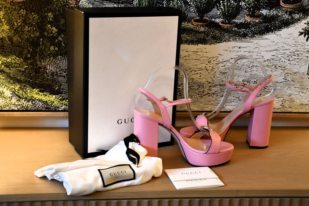 Preloved Pink high-heeled leather sandlals with Gucci packaging on a wooden surface
