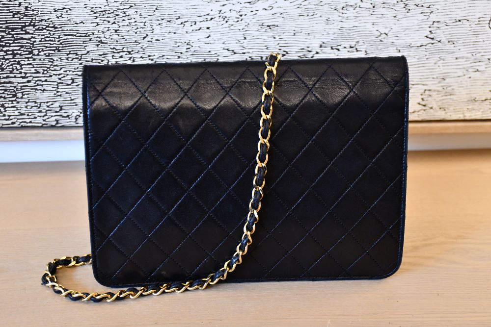 back of black quilted Chanel handbag with a gold leather entwined chain strap 